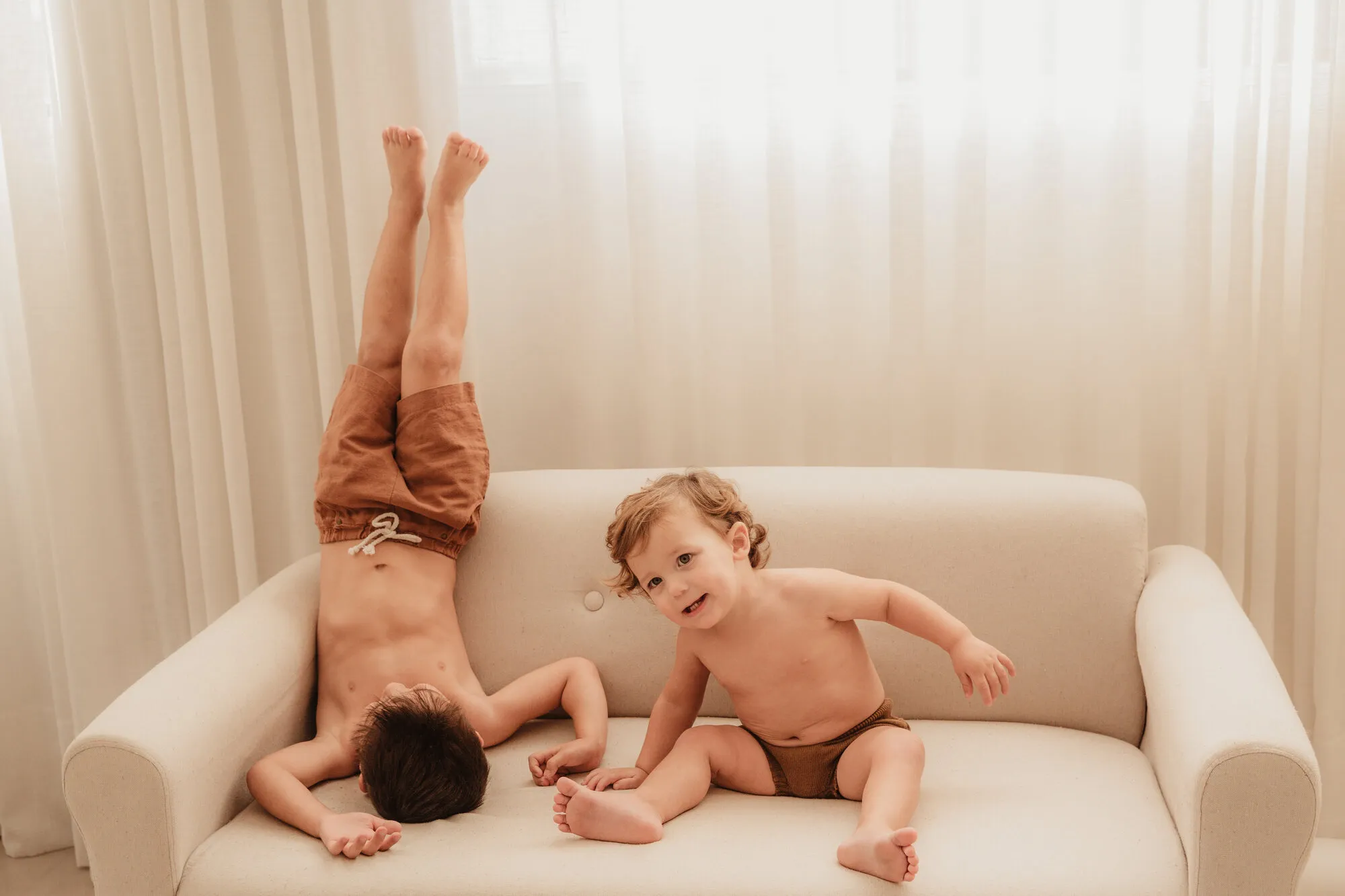 Duas crianças brincando no sofá durante ensaio de família em estúdio