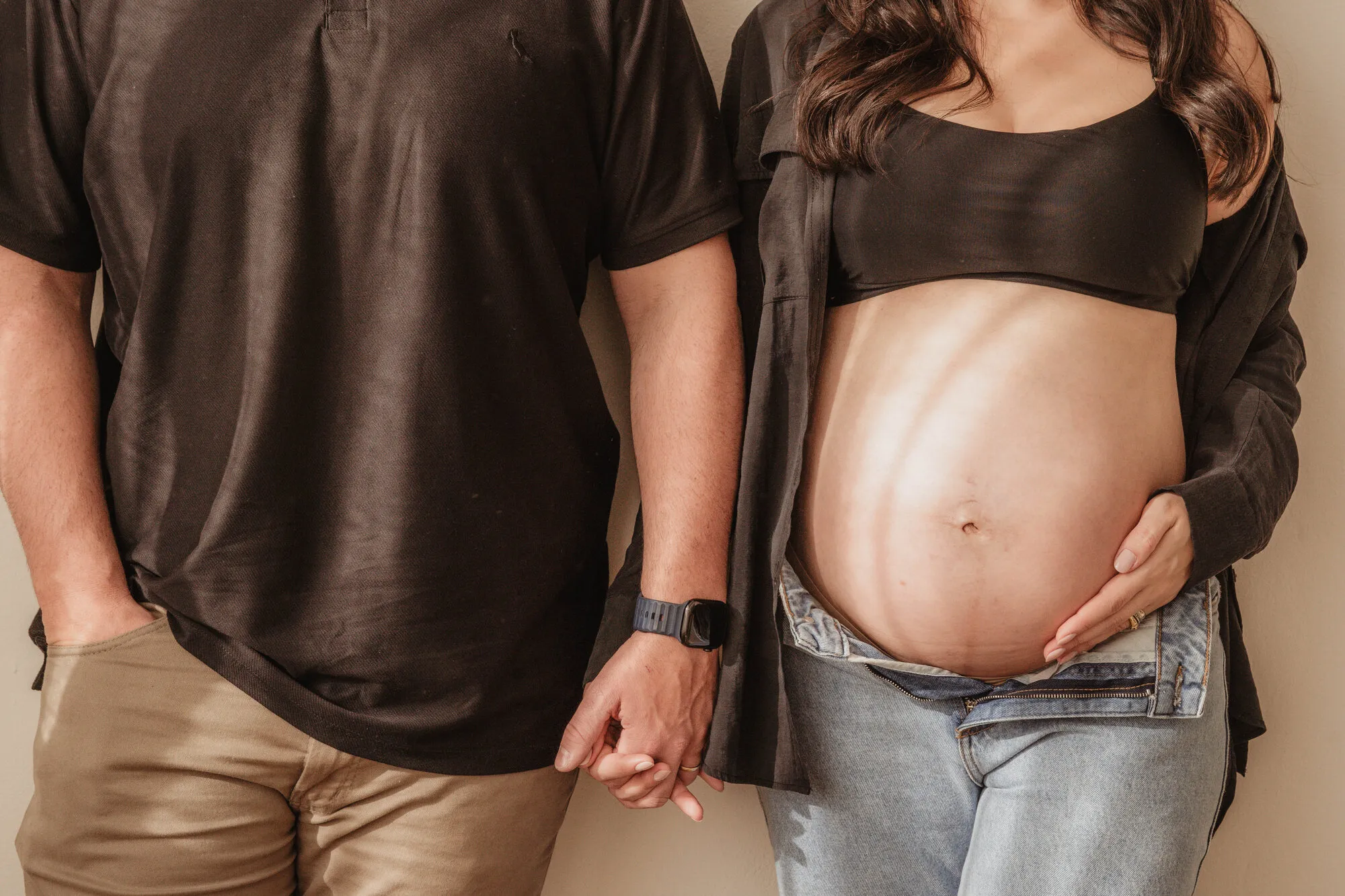Detalhe das mãos do casal sobre a barriga da gestante