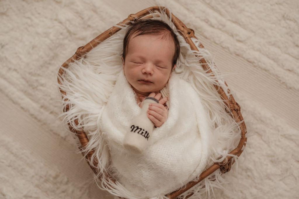 Bebê recém-nascido dormindo em cestinha durante ensaio newborn